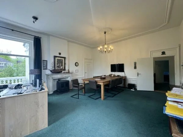 Vergaderruimte aan de Dorpsstraat met klassieke inrichting, houten tafel, open haard en groot raam met uitzicht.